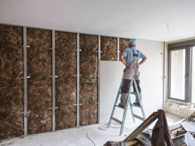 Construction site close up with workers making dry wall and implementing glass wool Earthwool-Acoustic.