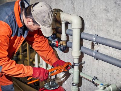 Plumber worker repairs the heating system in the house.